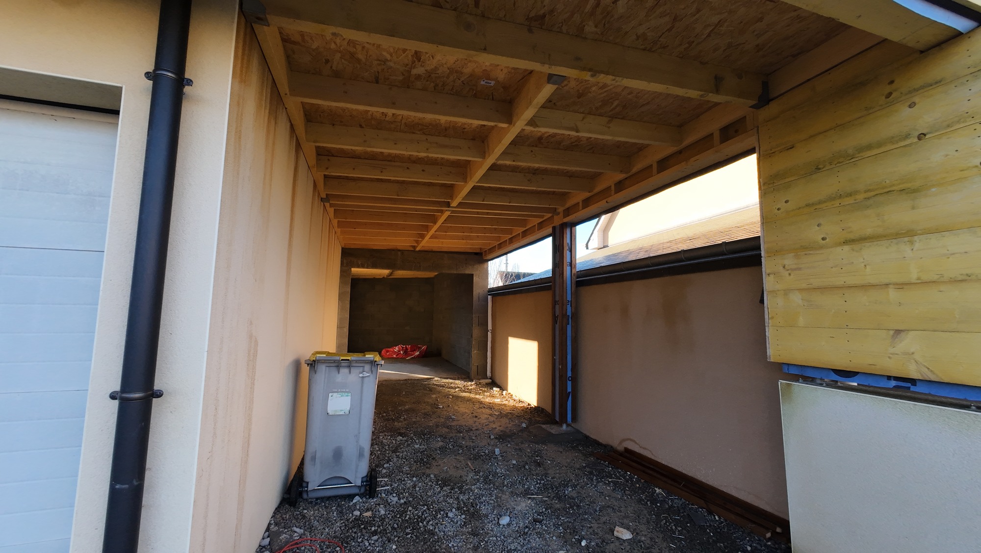 Vue intérieure de l’extension avec la structure bois du plafond et les murs en cours de réalisation